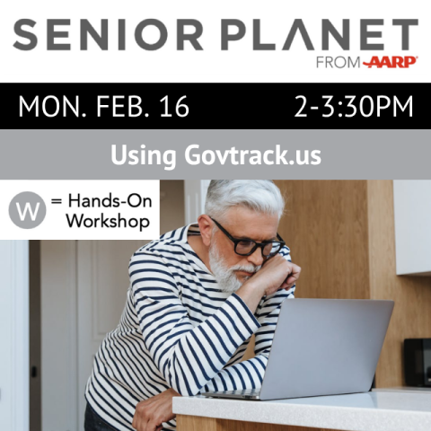 A person is leaning on a table and looking at an open laptap.