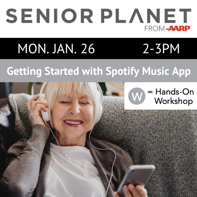 A person is smiling and wearing headphones while holding a phone.